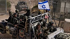 Soldados israelitas com a bandeira nacional num veículo blindado depois de atravessarem a vedação de segurança perto da chamada Linha Alfa, que separa Gola, controlada por Israel