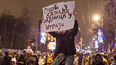 Des manifestants tiennent une banderole sur laquelle on peut lire "Les étudiants aux barrages, les travailleurs à la grève" devant le bâtiment de la télévision d'État à Belgrade, le 12 décembre 2024.