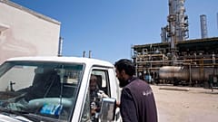 عامل ليبي يتحدث مع مسلحين يقومان بدورية بمصفاة نفط تسيطر عليها القوات المناهضة للعقيد القذافي في الضاحية الغربية لمدينة الزاوية في ليبيا. 19/08/2011