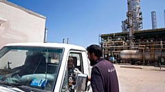 FILE - Líbiai munkás beszélget két lázadóval, akik a Kadhafi-ellenes erők által ellenőrzött olajfinomítóban járőröznek Zawiya nyugati peremén, 2011. augusztus 19., Líbia, 2011. augusztus 19.