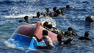 مهاجرون يسبحون بجوار قاربهم الخشبي المقلوب خلال عملية إنقاذ في جنوب جزيرة لامبيدوزا الإيطالية 
