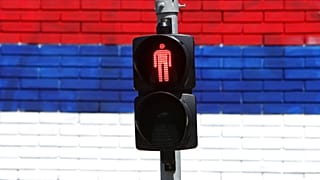 Foto de ficheiro: Um muro que mostra as cores da bandeira sérvia atrás de um semáforo em Belgrado, Sérvia, terça-feira, 18 de maio de 2021.