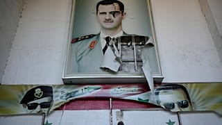 Um cartaz rasgado do falecido presidente sírio Hafez Assad e o seu filho, o presidente sírio deposto Bashar Assad, na entrada do famoso centro de detenção em Damasco.