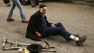 رجل إسرائيلي يتسول وهو يجلس على الأرض في سوق محاني يهودا في القدس