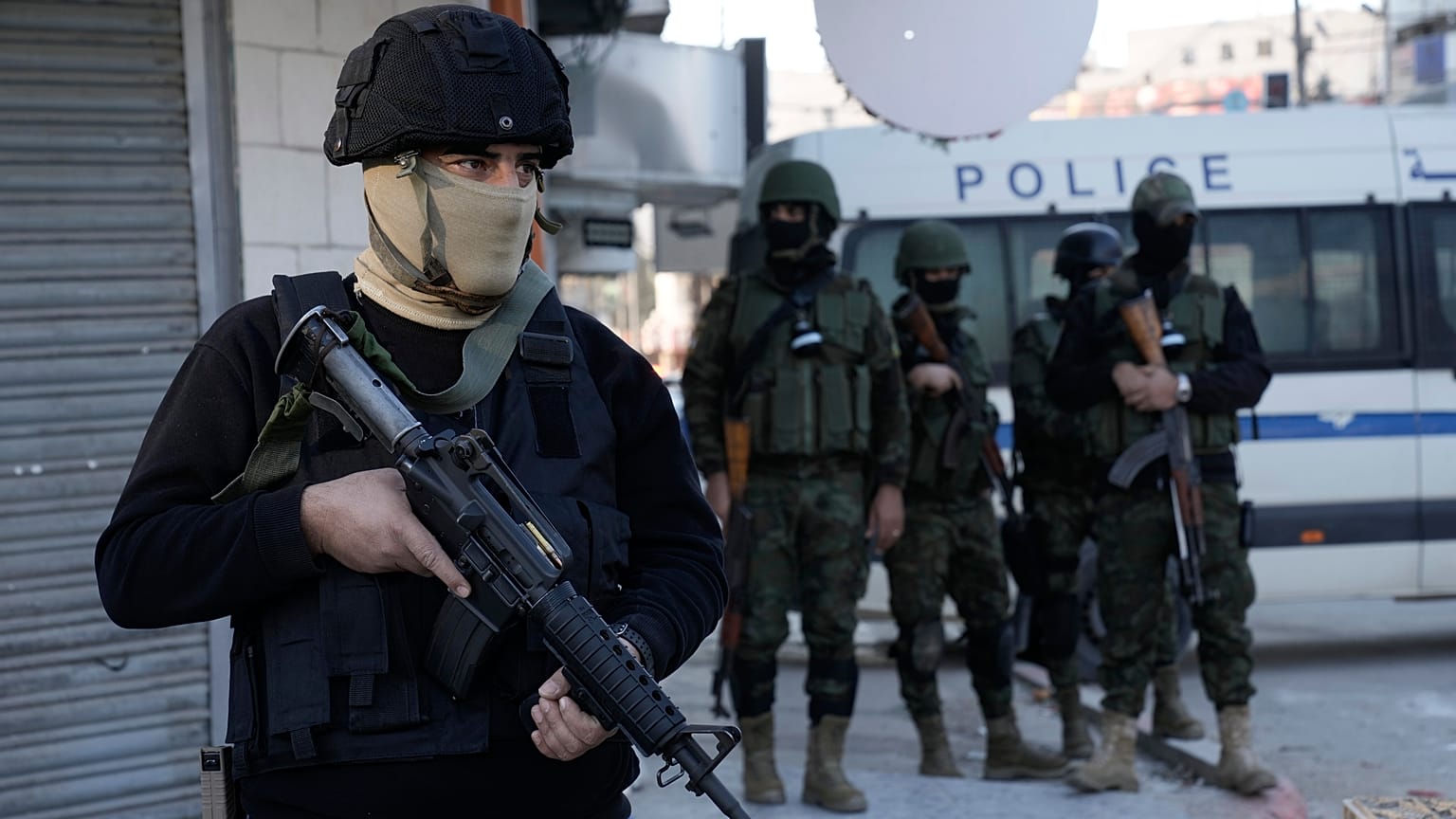 Um oficial da Autoridade Palestiniana segura a sua arma enquanto as forças de segurança palestinianas realizam uma grande incursão contra militantes no campo de refugiados de Jenin, a 16 de dezembro de 2024.