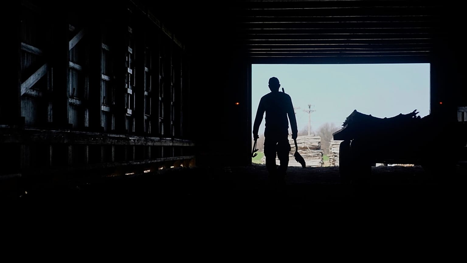 Contract worker from Mexico, carries tools back while doing maintenance inside a tobacco barn 