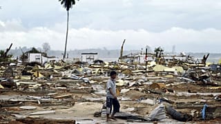 Endonezyalı bir adam 8 Ocak 2005 Cumartesi günü Açe eyaletindeki Banda Açe'nin 65 kilometre (40 mil) güney batısında bulunan Calang'daki kalıntılar arasında yürüyor.