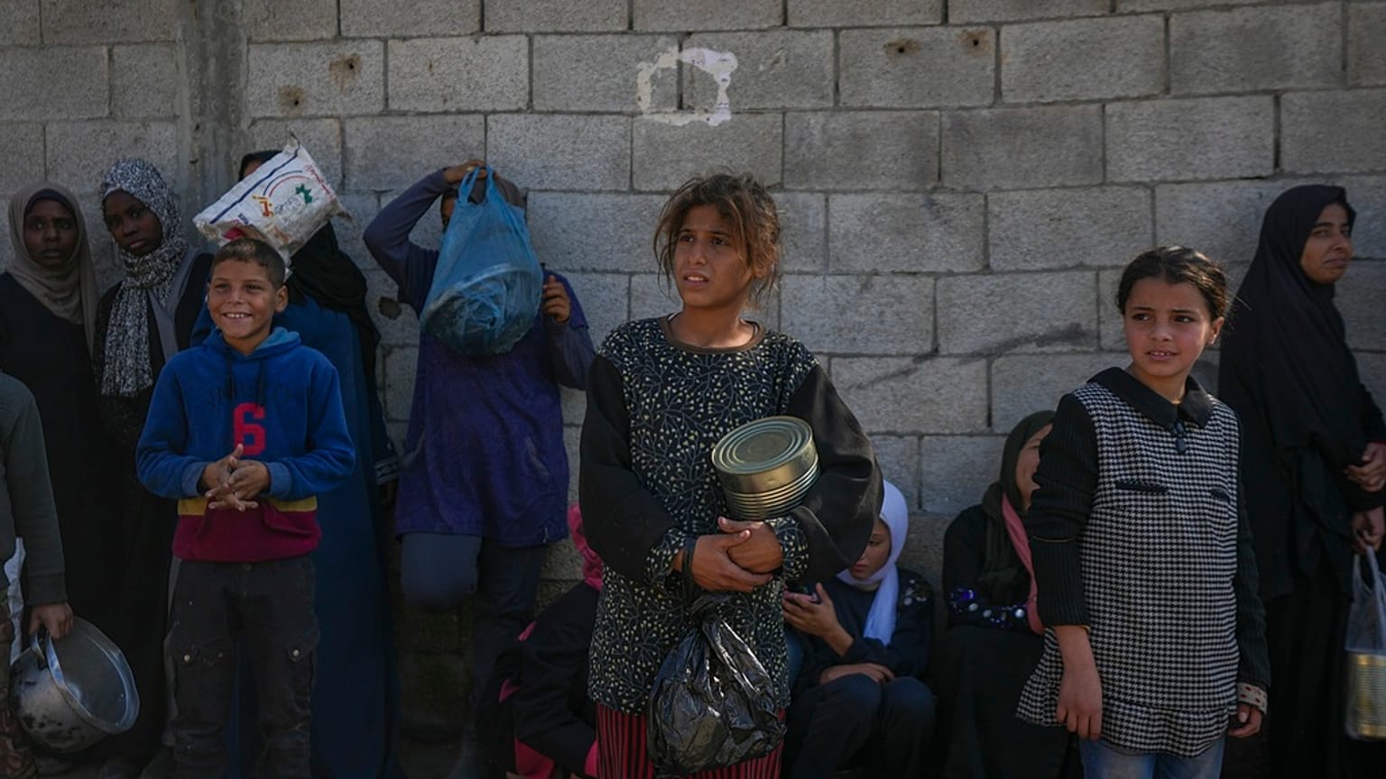 أطفال فلسطينيون ينتظرون الحصول على الطعام في مركز توزيع في دير البلح، قطاع غزة، الثلاثاء، 17 ديسمبر، 2024.