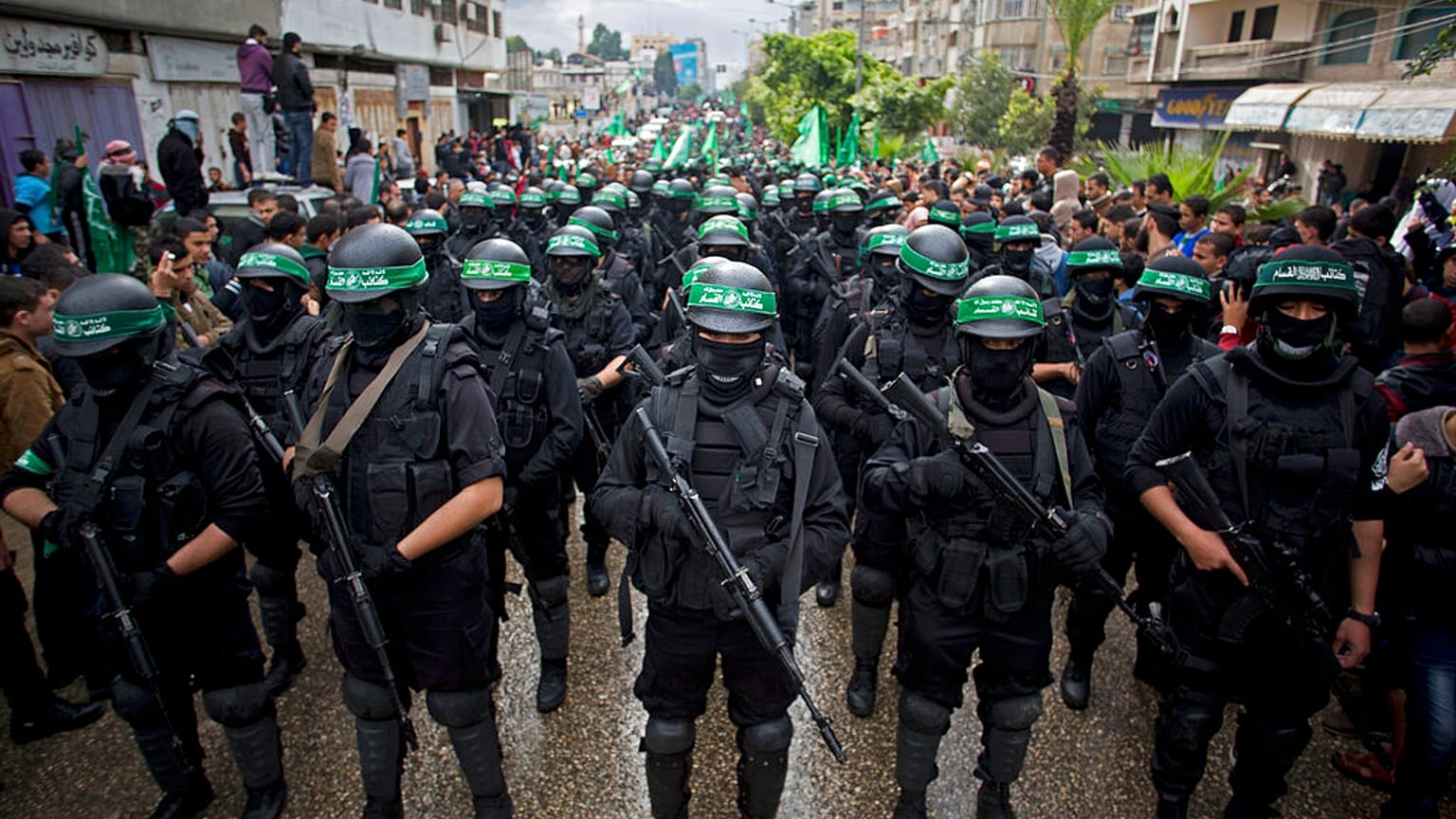 مسلحين فلسطينيين ملثمين من حركة حماس يحملون السلاح خلال مسيرة لإحياء الذكرى الـ27 لتأسيس الحركة في مدينة غزة.