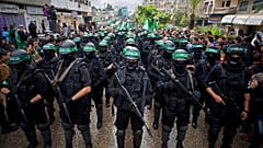 مسلحين فلسطينيين ملثمين من حركة حماس يحملون السلاح خلال مسيرة لإحياء الذكرى الـ27 لتأسيس الحركة في مدينة غزة.