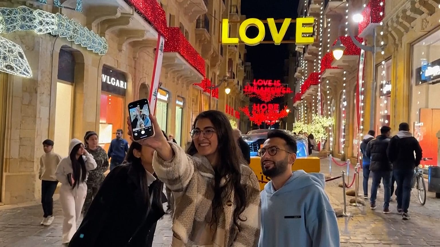 Giovani che scattano una foto davanti alle luminarie con messaggi di speranza, Beirut, Libano, 17.12.2024
