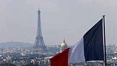 Le drapeau français avec la Tour Eiffel, le Dôme des Invalides et les toits vus depuis la colonnade du dôme du Panthéon à Paris.