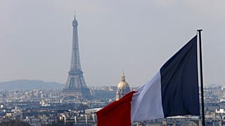 Le drapeau français avec la Tour Eiffel, le Dôme des Invalides et les toits vus depuis la colonnade du dôme du Panthéon à Paris.