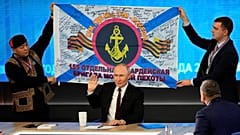 Des hommes tiennent une réplique de la bannière de la 155e brigade de marines de la flotte du Pacifique, lors de la conférence de presse annuelle du président russe Vladimir Poutine à Moscou, le 19 décembre 2024.