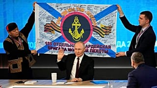 Homens seguram uma réplica do estandarte da 155.ª Brigada de Fuzileiros da Frota do Pacífico, durante a conferência de imprensa anual do Presidente russo Vladimir Putin, em Moscovo, a 19 de dezembro de 2024