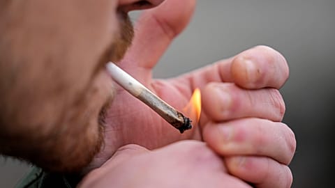 A man smokes cannabis in Cologne, Germany, at a public consumption event at the start of a new law in April 2024. 