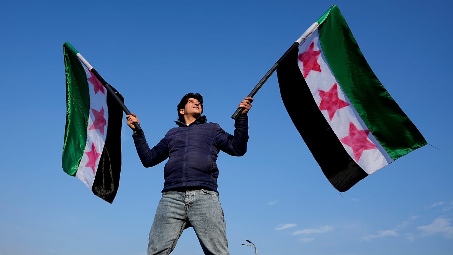 سوري يلوح بأعلام "الثورة" في ساحة الأمويين في دمشق، الجمعة 20 ديسمبر 2024.