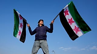 سوري يلوح بأعلام "الثورة" في ساحة الأمويين في دمشق، الجمعة 20 ديسمبر 2024.