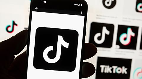 The TikTok logo is displayed on a mobile phone in front of a computer screen in Boston, 14 October, 2022