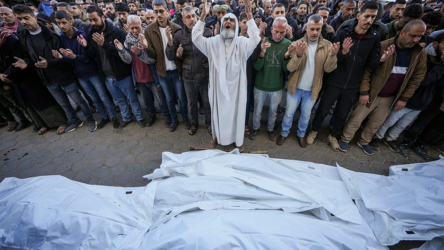Palesztinok imádkoznak egy házra mért izraeli csapás áldozatainak holttestei felett a temetés előtt az Al-Aksza Mártírok Kórháza előtt Deir al-Balahban, 2024. december 22.