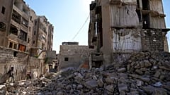 Des enfants syriens jouent à côté d'un immeuble résidentiel détruit dans le quartier de Hanano, dans la ville d'Alep, en Syrie.
