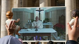 Fiéis assistem à bênção dominical do Papa num ecrã na Praça de São Pedro, no Vaticano, 22 de dezembro de 2024
