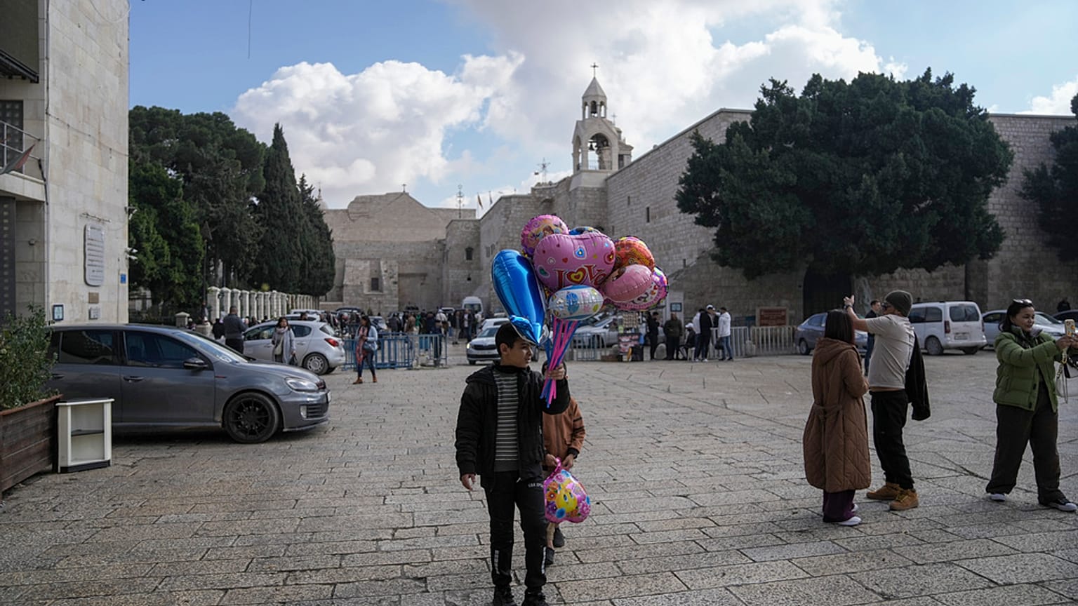 فتى يبيع البالونات خارج كنيسة المهد قبل عيد الميلاد في مدينة بيت لحم بالضفة الغربية 21 كانون الأول ديسمبر 2024