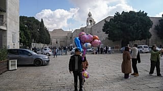 فتى يبيع البالونات خارج كنيسة المهد قبل عيد الميلاد في مدينة بيت لحم بالضفة الغربية 21 كانون الأول ديسمبر 2024