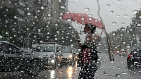 Um peão com um guarda-chuva na mão atravessa a rua durante uma chuva em Buenos Aires, Argentina, a 20 de março de 2024.