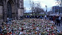 Des gens déposent des fleurs et allument des bougies devant l'église Saint-Jean près du marché de Noël de Magdebourg, en Allemagne, le dimanche 22 décembre 2024.