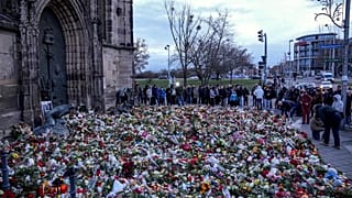 Des gens déposent des fleurs et allument des bougies devant l'église Saint-Jean près du marché de Noël de Magdebourg, en Allemagne, le dimanche 22 décembre 2024.