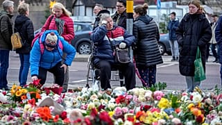 Люди возлагают цветы и свечи перед церковью Св.Иоанна недалеко от рождественской ярмарки, где в пятницу автомобиль въехал в толпу, Германия, 23 декабря 2024 г.
