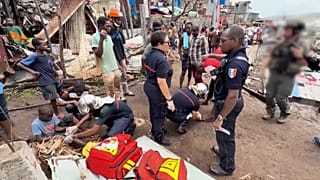 Medics tending to children as firefighters and security forces conduct search and rescue work
