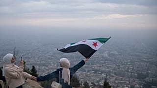 امرأة شابة تقف لالتقاط صورة وهي تلوح بعلم "الثورة" السورية في قمة على جبل قاسيون في دمشق، سوريا، السبت 21 ديسمبر 2024.