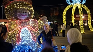 Νεαρή γυναίκα φωτογραφίζεται μπροστά σε χριστουγεννιάτικη διακόσμηση στη Δαμασκό