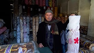 صاحب محل أقمشة في السوق القديم، داخل متجره في مدينة حلب القديمة، سوريا. يوم الأحد، 21 يناير/كانون الثاني 2018