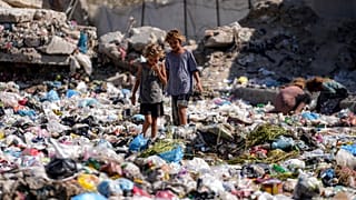 أطفال نازحون يفرزون القمامة في أحد الشوارع في دير البلح، وسط قطاع غزة.