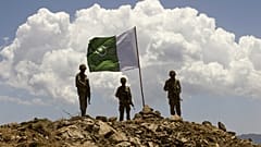 ARCHIVO: Una bandera paquistaní ondea sobre las tropas gubernamentales instaladas en lo alto de una posición de defensa en una antigua base de militantes talibanes que domina el valle del Swat, 22 de mayo de 2009.