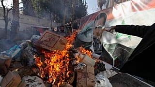 Bandeira do deposto Bashar al-Assad é colocada numa fogueira enquanto as forças rebeldes destroem drogas e álcool, encontrados num edifício complexo, em Damasco, Síria.
