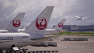 Japan Airlines uçağı, bir diğeri Tokyo'daki Haneda uluslararası havalimanından havalanırken terminalde park halinde duruyor