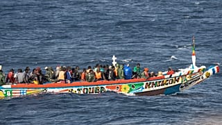 Migranten drängen sich in einem Holzboot, während sie zum Hafen von La Restinga auf der Kanareninsel El Hierro, Spanien, fahren, Montag, 19. August 2024.