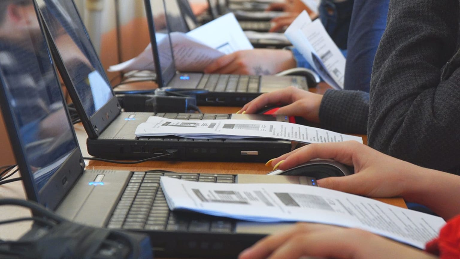 Öğrenciler bir sınıfta, laptoplarda çalışıyor.