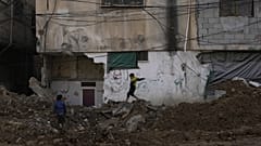Çocuklar, İsrail'in Batı Şeria'daki Tulkarem Mülteci Kampı'na düzenlediği saldırının ardından zarar gören binaların önünde