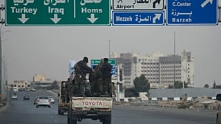 Combattenti siriani viaggiano su veicoli, mentre pattugliano un'autostrada, a Damasco, in Siria, giovedì 26 dicembre 2024.