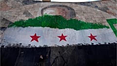 طفل سوري يقف تحت صورة عملاقة للرئيس السوري الراحل حافظ الأسد مطلية بألوان علم الثورة في دمشق، سوريا، الخميس 26 ديسمبر 2024.