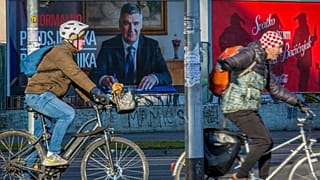 Des cyclistes passent devant une affiche du président sortant Zoran Milanović avant l'élection présidentielle à Zagreb, en Croatie, le jeudi 26 décembre 2024