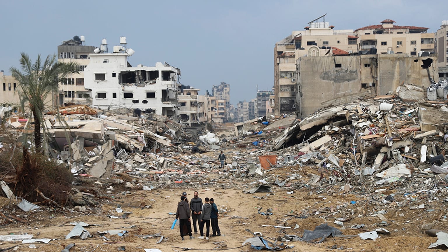 فلسطينيون يسيرون بجوار المبنى الذي دمره القصف الإسرائيلي لقطاع غزة في مدينة غزة يوم الأربعاء، 3 يناير، 2024.