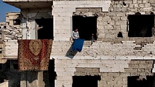 Casal de idosos sírios regressa a casa em ruínas no subúrbio de Harasta, cidade fantasma de Damasco