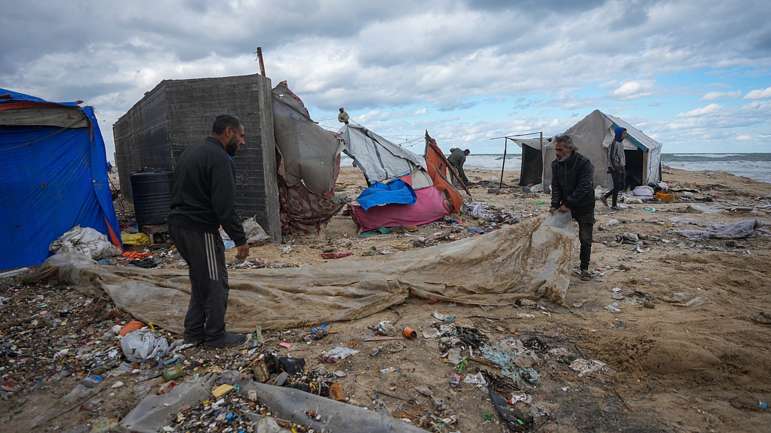 فلسطينيون ينصبون خيمة في مخيم للنازحين على شاطئ البحر في دير البلح بقطاع غزة، الثلاثاء 26 نوفمبر/تشرين الثاني 2024