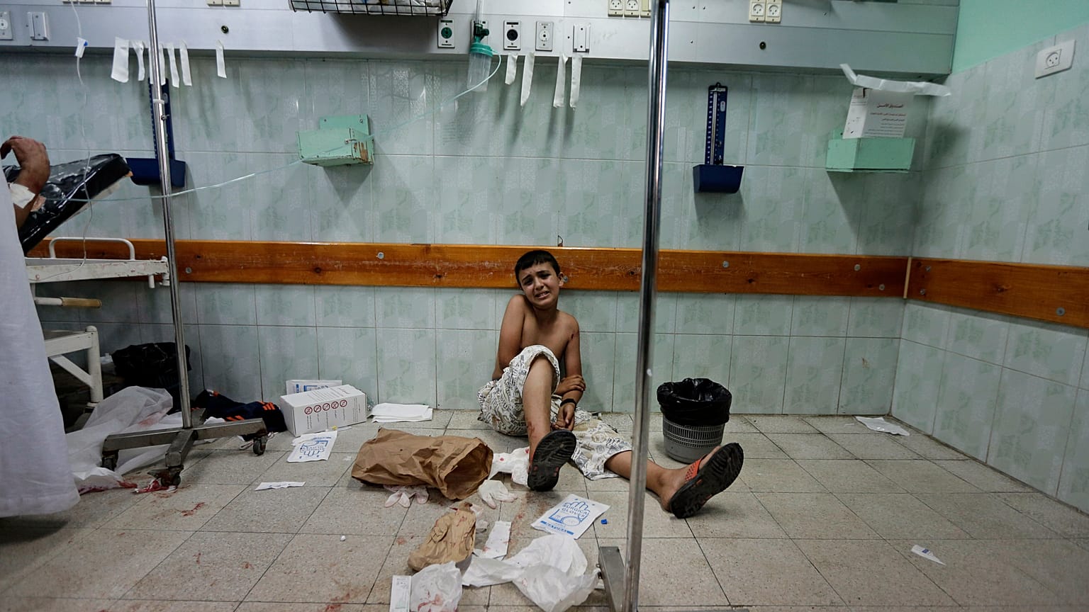 Un ragazzo palestinese ferito da un attacco israeliano siede sul pavimento del pronto soccorso dell'ospedale Kamal Adwan, 3 agosto 2014.